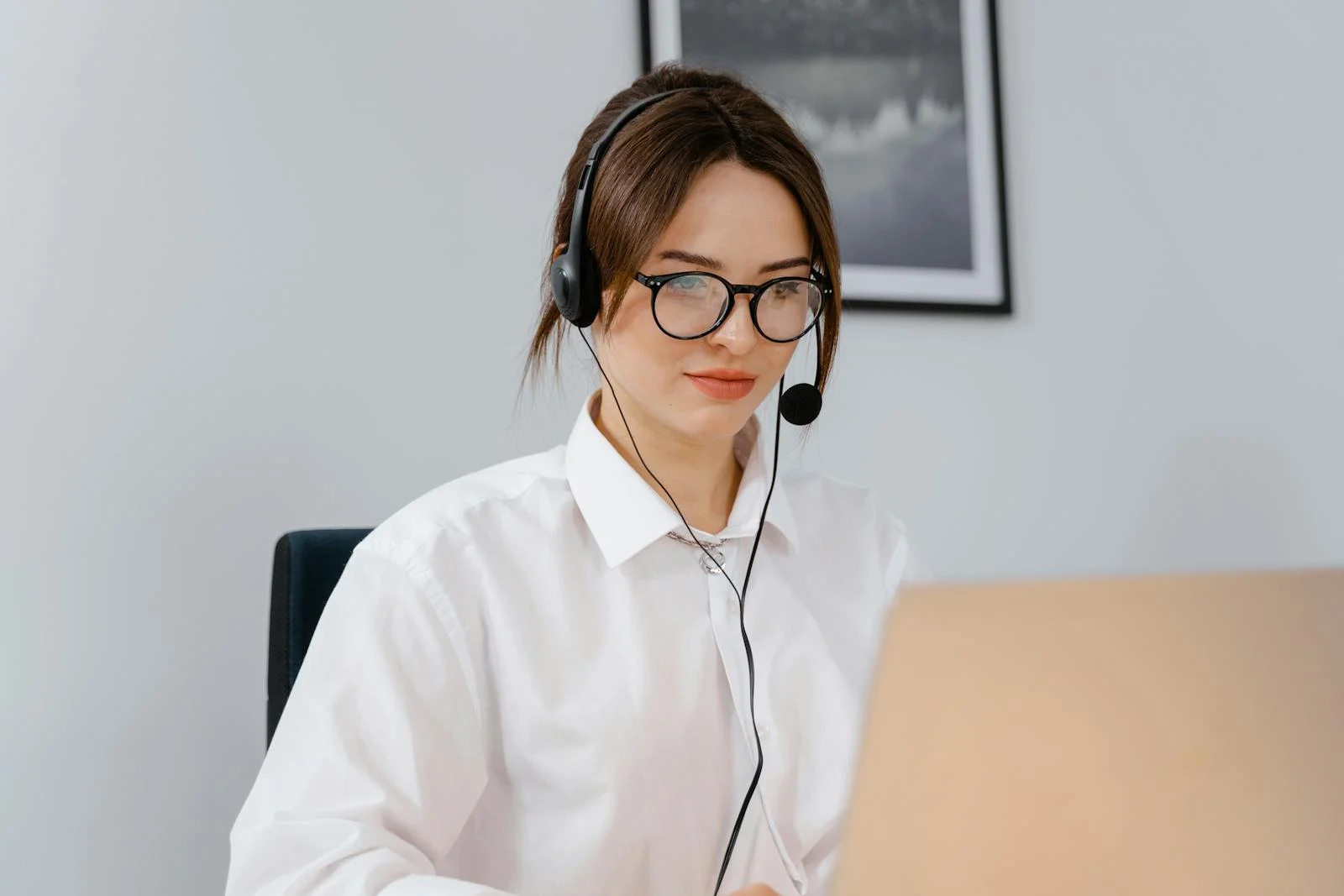 Customer support representative using a laptop and headset, representing a client portal backed by human service