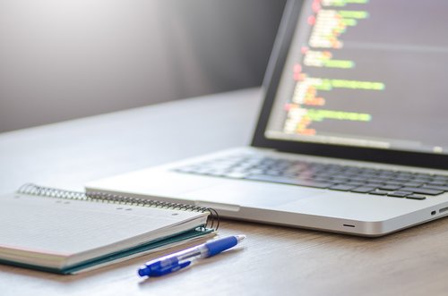 Laptop and notes on a desk, representing cost comparison and platform planning for a small business website.